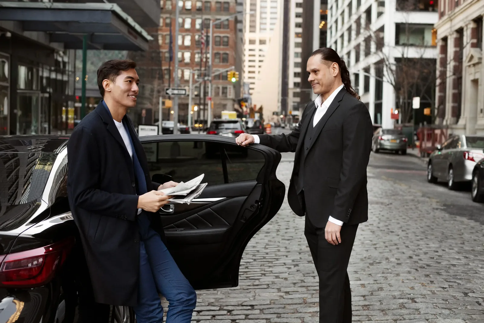 Chauffeur greeting a client beside a black car on arrival